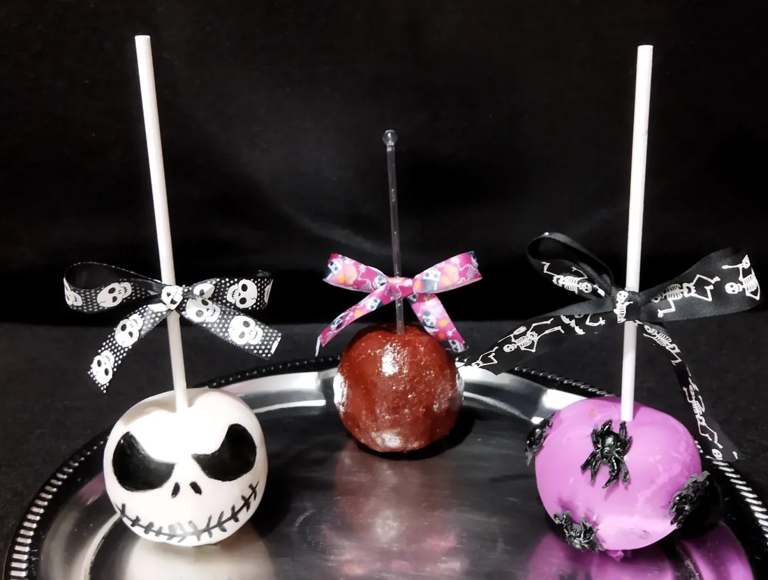 Tres manzanas de Halloween: calavera, roja y morada con araña, con moños de colores