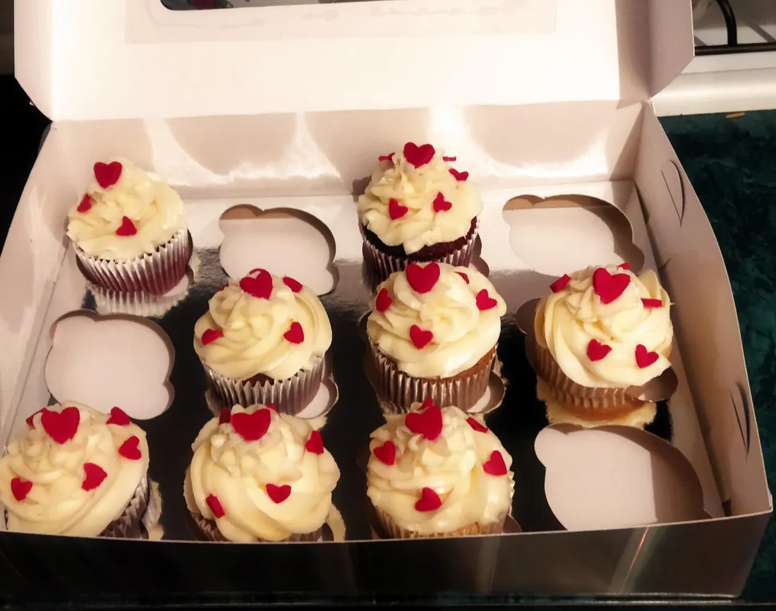 Caja de cupcakes de chocolate con betún blanco y corazones rojos